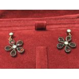 A pair of daisy-style earrings set with garnets an