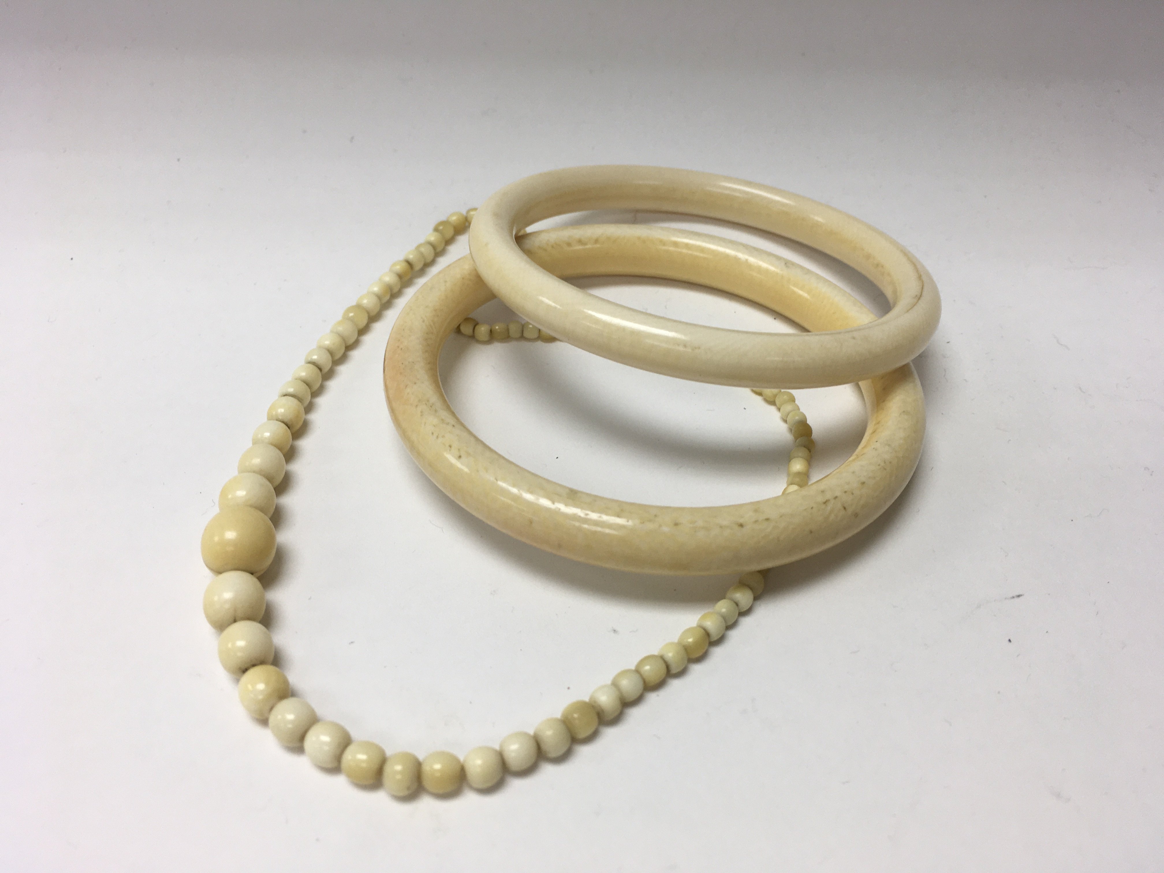 2 ivory bangles and a graduated ivory bead necklac