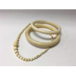 2 ivory bangles and a graduated ivory bead necklac