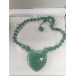 A large jade heart shaped pendant.