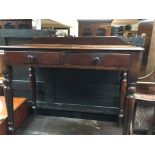 A Victorian side table with with a raised back above two drawers on turned legs.