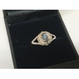 A 9carat white gold ring set with a cabochon flanked by small chip stone diamonds ring size N