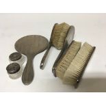 A silver backed hand mirror and two matching sets of brushes.