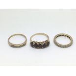 Three gold rings, one set with garnets, the others