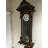 A walnut cased Vienna type wall clock with an arched pediment and enamel dial.