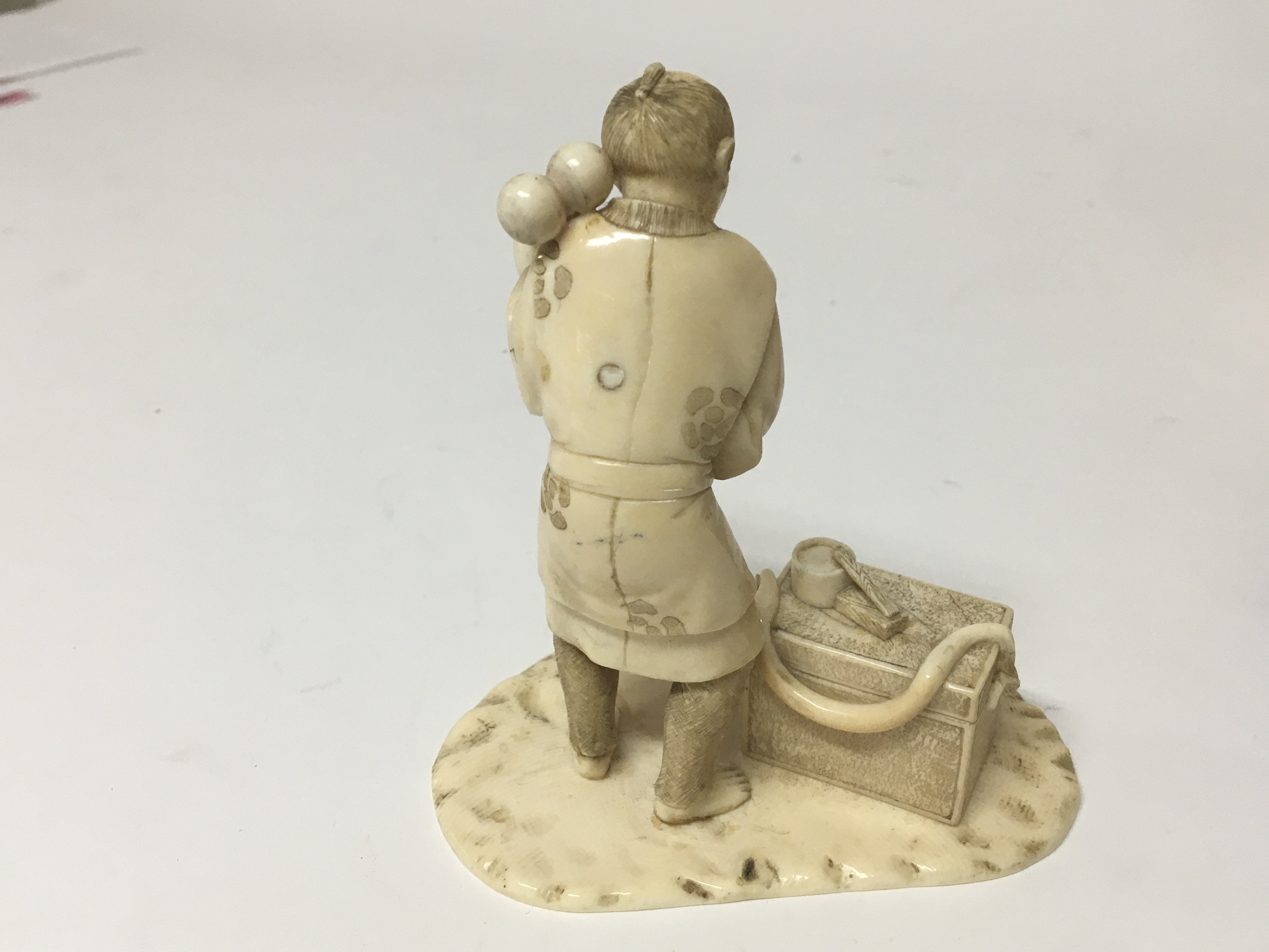A late 19th century Japanese ivory carving of a craftsman with a chest of tools on a shaped base. - Image 2 of 3