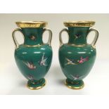 A pair of Minton loop handled vases decorated with brightly painted birds in flight on a green