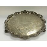 A three footed silver tray with a shaped edge having shell motifs. Birmingham hallmarks. Approx