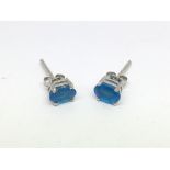 A pair of silver studs set with neon blue apatite.