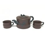 A Chinese tea set with tea pot and two cups, in the shape of bamboo with applied stylised leaves