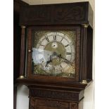 An oak longcase clock with a brass dial and silver chapter ring and carved case the brass dial