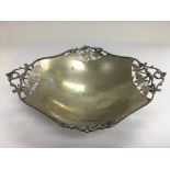 A silver dish with piercework decoration and raised on four feet, marked 800.