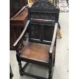 A 17th century carved oak open arm chair with a panelled back and turned supports. Some later