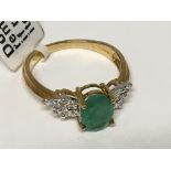 A 9carat gold ring set with an Emerald coloured stone flanked by baguette diamonds. ring size M-N
