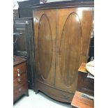 An Edwardian bow fronted wardrobe with satinwood cross banding and inset oval panel's height 175x115