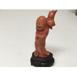 A carved coral figure in the form of a Buddha on a carved base some slight damage. Height 10.5cm