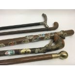 Five various walking sticks, including two with tourist crests, one with brass handle and one with a