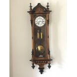 A Victorian walnut Vienna type with a white enamel dial with ebony finials.