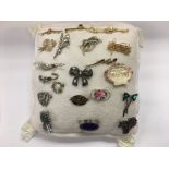 A collection of approx 20 brooches set on a cushio