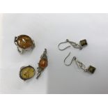 A collection of silver jewellery inset with amber including two rings a brooch and a pair of