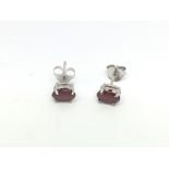 A pair of silver studs set with treated rubies.