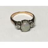 An unmarked gold ring set with an opal flanked by two diamonds ring size J.