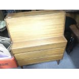 A modern design Teak bureau with a fall front above three drawers.