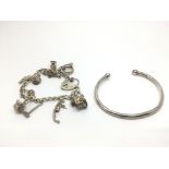 A silver charm bracelet and a silver torque bangle (2).