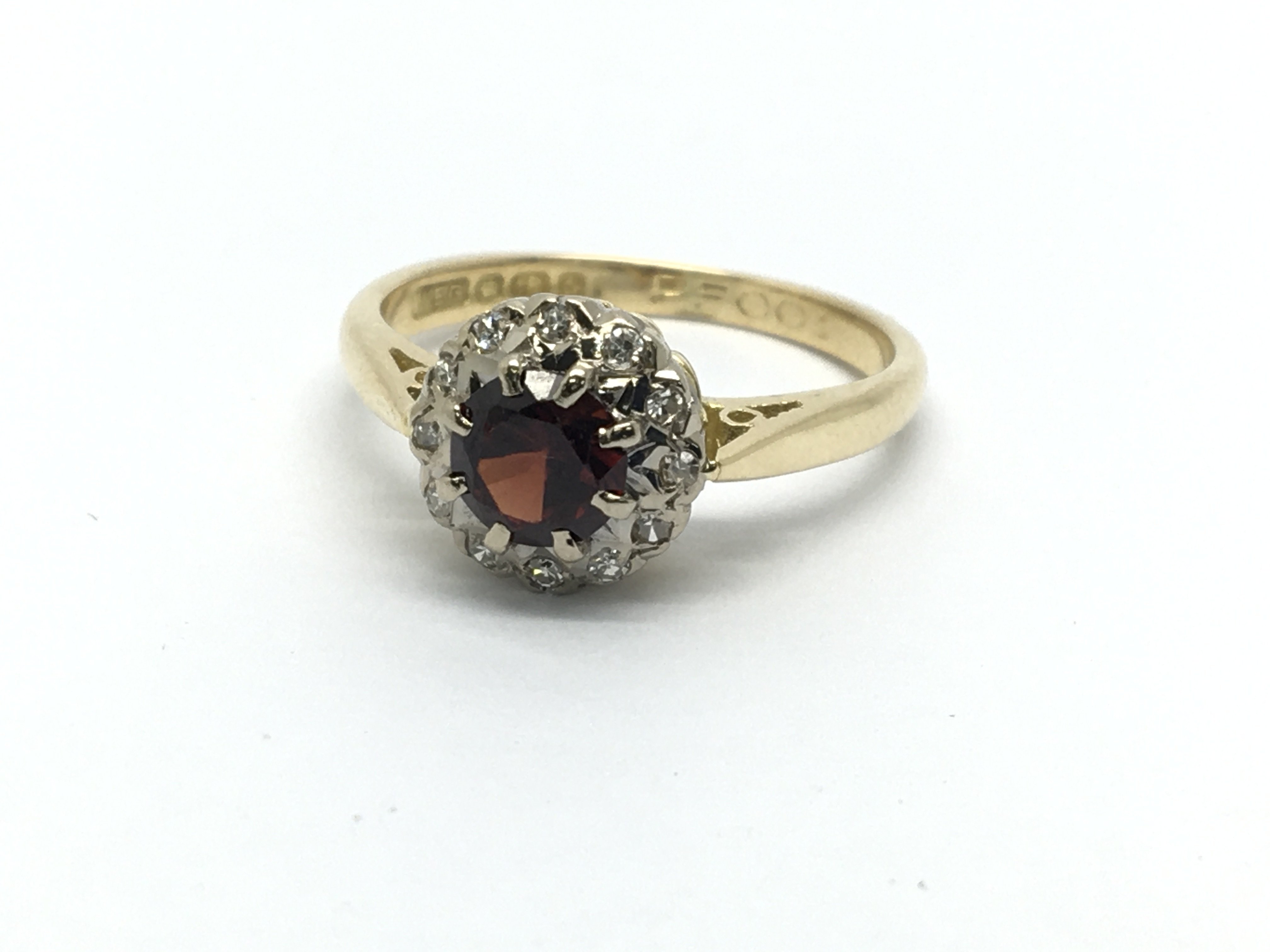 An 18ct gold ring set with a central garnet and su