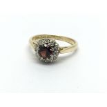 An 18ct gold ring set with a central garnet and su