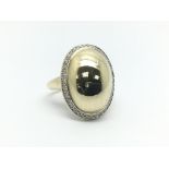 A 9ct gold ring of oval design with a diamond surr