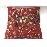 A variety of vintage brooches displayed on a red cushion