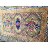 A hand knotted Middle Eastern rug with three central medallion on a green ground 235x150cm