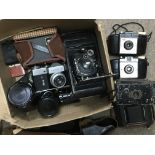 A box of cameras and photographic accessories including a Zenit B SLR, three folding cameras and