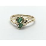 A gold ring set with two emeralds and two small diamonds, approx 2.2g and approx size J-K.