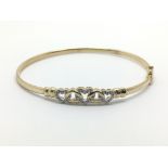 A gold bangle with heart shaped decoration with small diamonds, approx 4.6g.