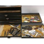 A flight of drawers containing pen knives.