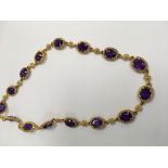 A 9 ct gold necklace inset with 14 amethyst stones