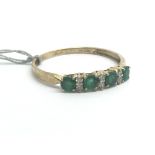 A 9ct yellow gold ring set with a row of emeralds