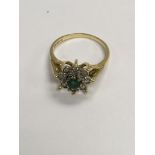 A 18 ct gold ring inset with light emerald surroun