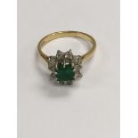 A 18 ct gold ring inset with a square emerald surr