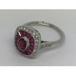 A platinum ring set with central ruby, a halo of c