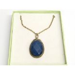 A large blue stone pendant on chain, in box