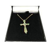 A 9ct gold emerald and diamond cross on a 9ct gold
