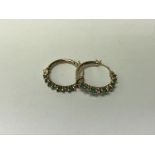 A pair of 10ct gold hoop earrings set with emerald