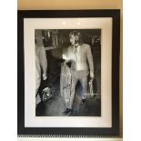 George Best Signed Framed Photo: Depicts Best holding suit bag and brief case whilst dressed in a