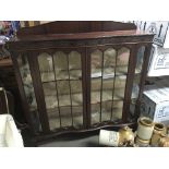 A Mahogany display cabinet with glazed doors enclosing shelfs on ball and claw feet. one end glass