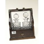 A two bottled cut glass decanter tantalus with a mahogany frame and key.
