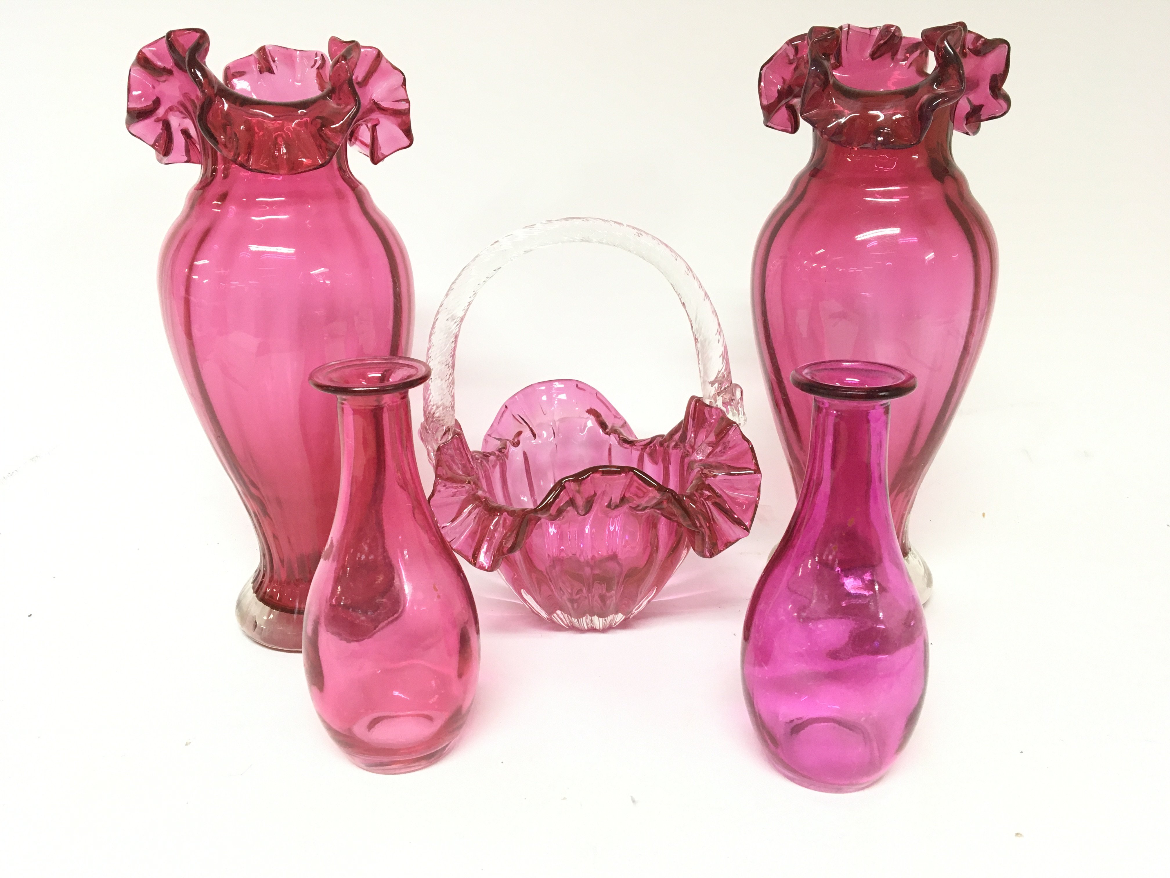 A pair of cranberry glass vases a basket and two bottle vases.