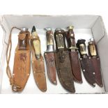 Seven vintage knives in original leather sheaths.